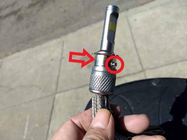 The securing screw is shown circled. The arrow is pointing to the collar that should be removed and will not be used. There will be a nut behind the collar which will fall out once the screw is removed. Be careful to not lose this nut as it will be reused